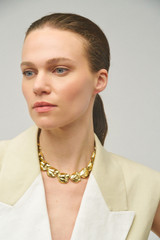 Profile view of model wearing the Oroton Tulip Necklace in Gold and Brass for Women