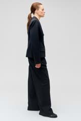 Profile view of model wearing the Oroton Slouch Pant in Black and 53% polyester, 42% virgin wool, 5% elastane for Women