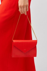 Profile view of model wearing the Oroton Mia Texture Clutch in True Red and Textured leather for Women