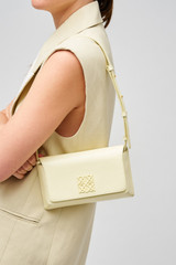 Profile view of model wearing the Oroton Della Texture Small Baguette in Lemon Curd and Textured leather for Women