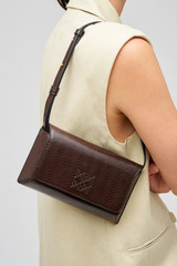 Profile view of model wearing the Oroton Della Texture Small Baguette in Mahogany and Textured leather for Women