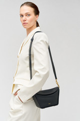 Profile view of model wearing the Oroton Fable Small Day Bag in Black and Smooth leather for Women