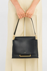 Profile view of model wearing the Oroton Elm Medium Satchel Bag in Black and Smooth Pebble Leather for Women