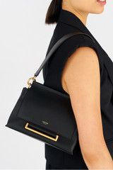 Profile view of model wearing the Oroton Elm Small Satchel Bag in Black and Smooth Pebble Leather for Women