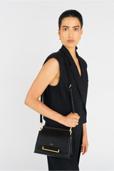 Profile view of model wearing the Oroton Elm Small Satchel Bag in Black and Smooth Pebble Leather for Women