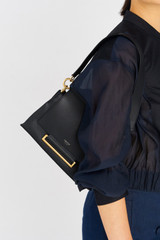 Profile view of model wearing the Oroton Elm Small Satchel Bag in Navy and Smooth Pebble Leather for Women