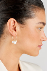 Profile view of model wearing the Oroton Kimberley Pearl Charm Hoop Earrings in Gold/Pearl and Brass for Women
