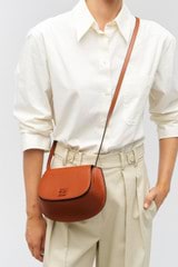 Profile view of model wearing the Oroton Della Saddle Shoulder Bag in Syrup and Smooth leather for Women