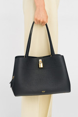 Profile view of model wearing the Oroton Tate Three Pocket Day Bag in Black and Pebble leather for Women