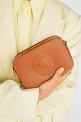 Profile view of model wearing the Oroton Polly Smooth Zip Around Crossbody in Cognac and Smooth leather for Women