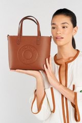 Profile view of model wearing the Oroton Polly Smooth Small Tote in Cognac and Smooth leather fused with saffiano PU for Women