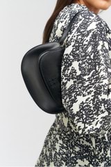 Profile view of model wearing the Oroton Della Saddle Shoulder Bag in Black and Smooth leather for Women