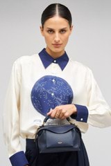 Profile view of model wearing the Oroton Mica Mini Bowler in North Sea and Pebble leather for Women