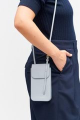 Profile view of model wearing the Oroton Margot Phone Crossbody in Dusk Blue and Pebble leather for Women