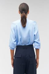 Profile view of model wearing the Oroton Tie Neck Shirt in Delft Blue and 100% silk for Women