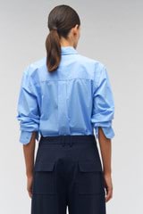 Profile view of model wearing the Oroton Poplin Long Sleeve Shirt in Delft Blue and 100% cotton for Women