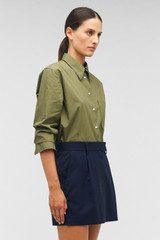 Profile view of model wearing the Oroton Poplin Long Sleeve Shirt in Green Olive and 100% cotton for Women