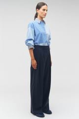 Profile view of model wearing the Oroton Pleat Pant in North Sea and 98%  wool, 2% elastane for Women
