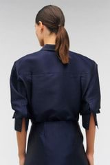 Profile view of model wearing the Oroton Fringe Beaded Satin Overshirt in North Sea and 85% polyester, 15% silk for Women