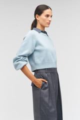 Profile view of model wearing the Oroton Crop Crew Sweater in Windmill Blue and 100% wool for Women