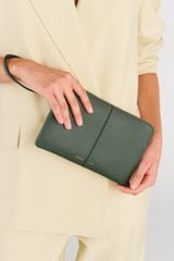 Profile view of model wearing the Oroton Lilly Medium Zip Pouch in Fern and Pebble leather for Women