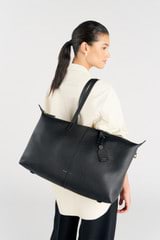 Profile view of model wearing the Oroton Lilly Weekender Tote in Black and Pebble leather for Women