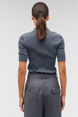 Profile view of model wearing the Oroton Stitch Rib Polo in Charcoal Marle and 100% wool for Women