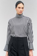 Profile view of model wearing the Oroton High Neck Check Blouse in Black/White and 92% silk, 8% spandex for Women