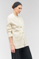 Profile view of model wearing the Oroton Button Detail Long Line Cardigan in Cream and 100% wool for Women