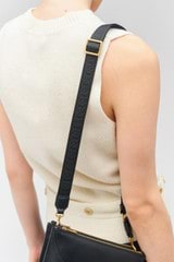 Profile view of model wearing the Oroton Logo Narrow Webbing Strap in Black/Black and Smooth leather for Women