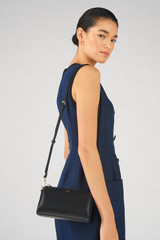 Profile view of model wearing the Oroton Harvey Baguette Crossbody in Black and Smooth leather for Women