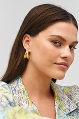 Profile view of model wearing the Oroton Alma Hoops in Worn Gold and Brass for Women