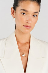 Profile view of model wearing the Oroton Kimberley Pearl Charm Necklace in Gold/Pearl and Brass for Women
