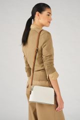 Profile view of model wearing the Oroton Iris Double Zip Crossbody in Cream and Pebble leather. Smooth leather for Women