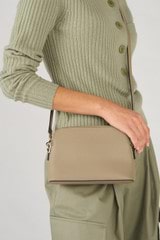Profile view of model wearing the Oroton Iris Double Zip Crossbody in Mushroom and Pebble leather. Smooth leather for Women