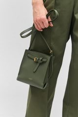 Profile view of model wearing the Oroton Margot Tiny Bucket Bag in Moss and Pebble leather for Women