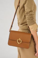 Profile view of model wearing the Oroton Ali Medium Satchel in Cognac and Smooth leather for Women