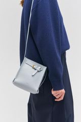 Profile view of model wearing the Oroton Margot Tiny Bucket Bag in Dusk Blue and Pebble leather for Women