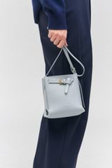 Profile view of model wearing the Oroton Margot Tiny Bucket Bag in Dusk Blue and Pebble leather for Women