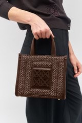 Profile view of model wearing the Oroton Lane Straw Small Tote in Mahogany and Woven straw with leather trims for Women