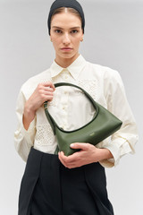Profile view of model wearing the Oroton Cinder Mini Baguette in Moss and Smooth leather for Women