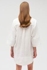 Profile view of model wearing the Oroton Embroidered Tunic Dress in Antique White and 100% linen for Women