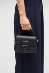 Profile view of model wearing the Oroton Carter Mini Day Bag in Black and Smooth leather for Women