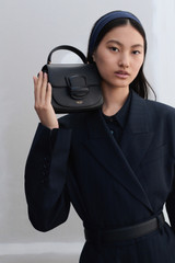 Profile view of model wearing the Oroton Carter Mini Day Bag in Black and Smooth leather for Women