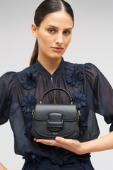 Profile view of model wearing the Oroton Carter Mini Day Bag in Black and Smooth leather for Women