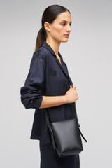 Profile view of model wearing the Oroton Ellis Crossbody in Black and Smooth leather for Women