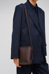 Profile view of model wearing the Oroton Ellis Crossbody in Mahogany and Smooth leather for Women