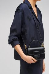 Profile view of model wearing the Oroton Carter Texture Mini Day Bag in Black and Embossed leather for Women