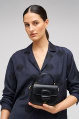 Profile view of model wearing the Oroton Carter Texture Mini Day Bag in Black and Embossed leather for Women