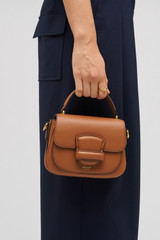 Profile view of model wearing the Oroton Carter Mini Day Bag in Brandy and Smooth leather for Women